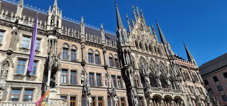 Gothic spires and stone carvings of Munich's New Town Hall facade shot from below against a deep blue sky