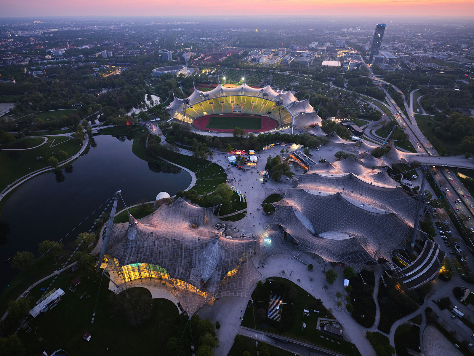Aerial view of Olympiapark Munich at dusk with Olympic Stadium and lake