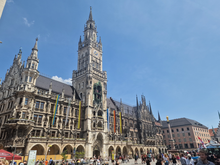 Marienplatz New Town Hall and Glockenspiel tower in Munich on a sunny summer day with crowds in the square