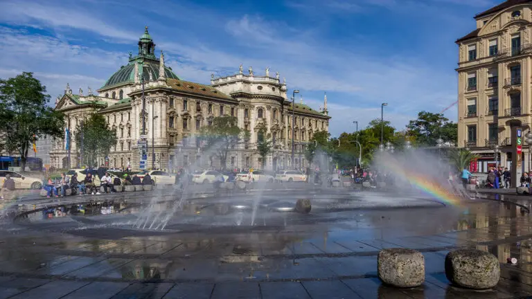 Fountain spray casting a rainbow in front of the Palace of Justice at Karlsplatz Stachus, Munich