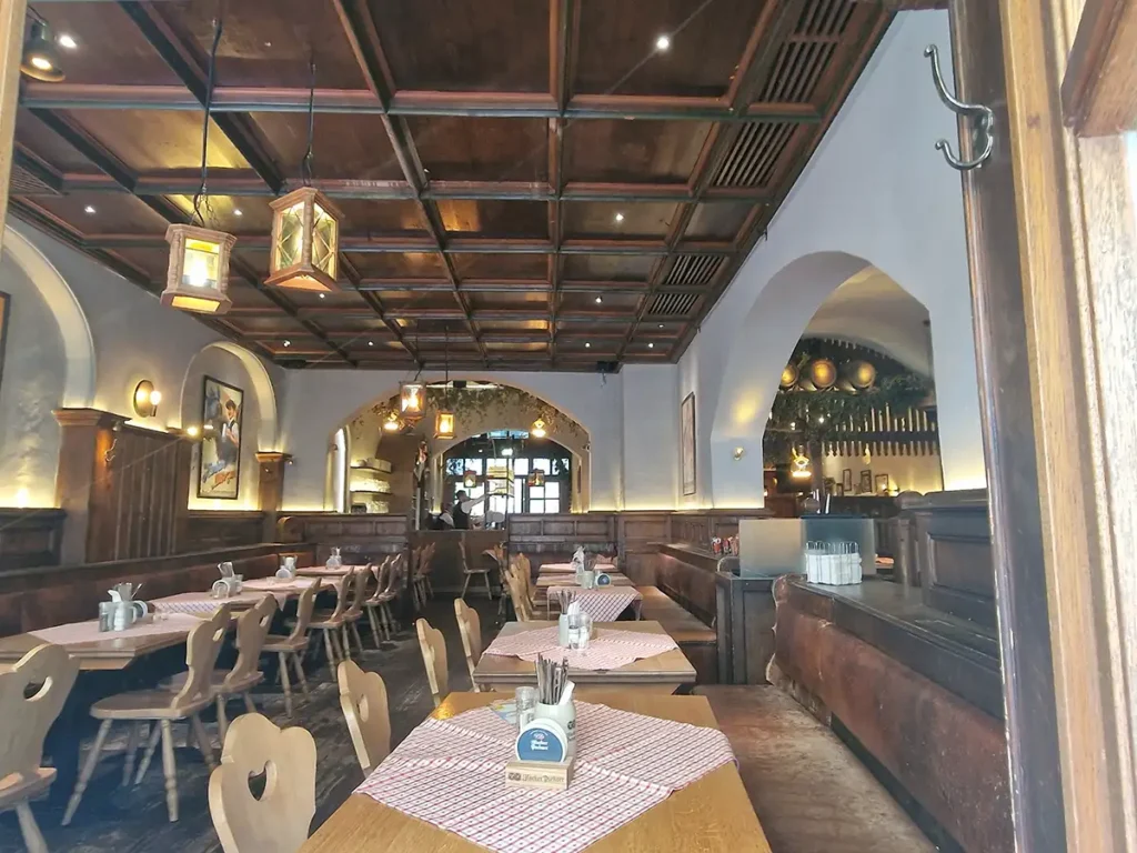 Interior of a traditional Bavarian restaurant in Munich with wooden ceiling and checkered tablecloths