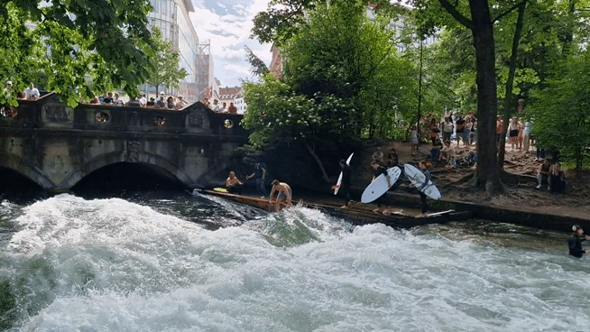 Surfers riding the Eisbachwelle near the English Garden in Munich