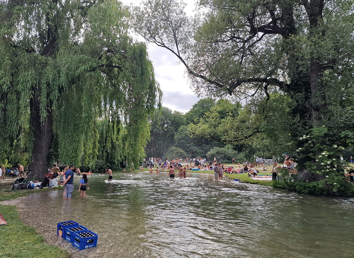 People relaxing by the stream in the English Garden in Munich on a summer day