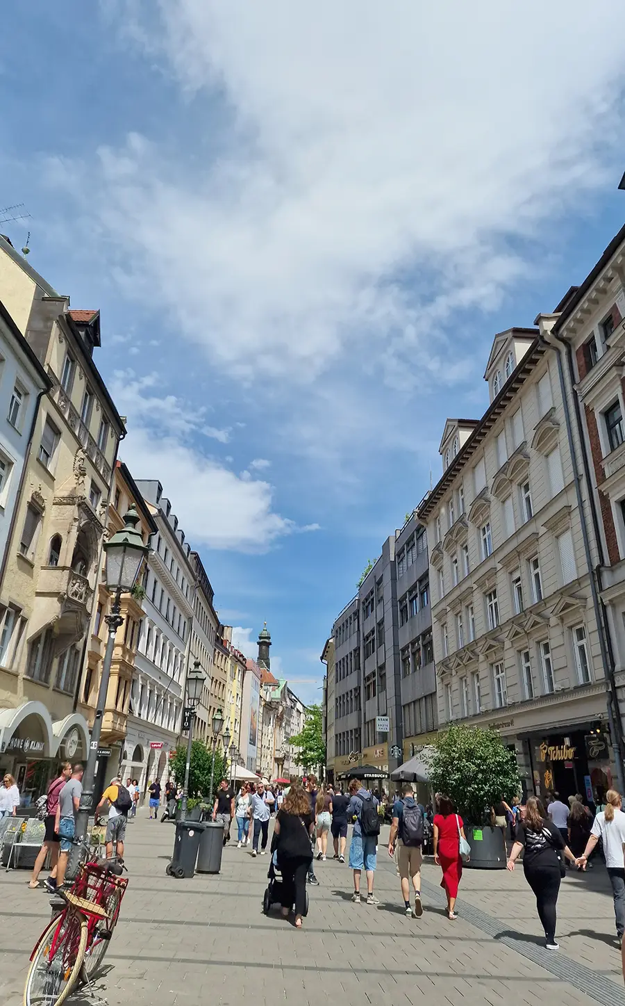 Paved pedestrian street in Munich old town with people walking on a summer day
