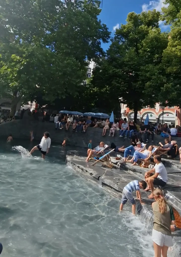 People cooling off at the Rindermarkt fountain during a summer heatwave in Munich