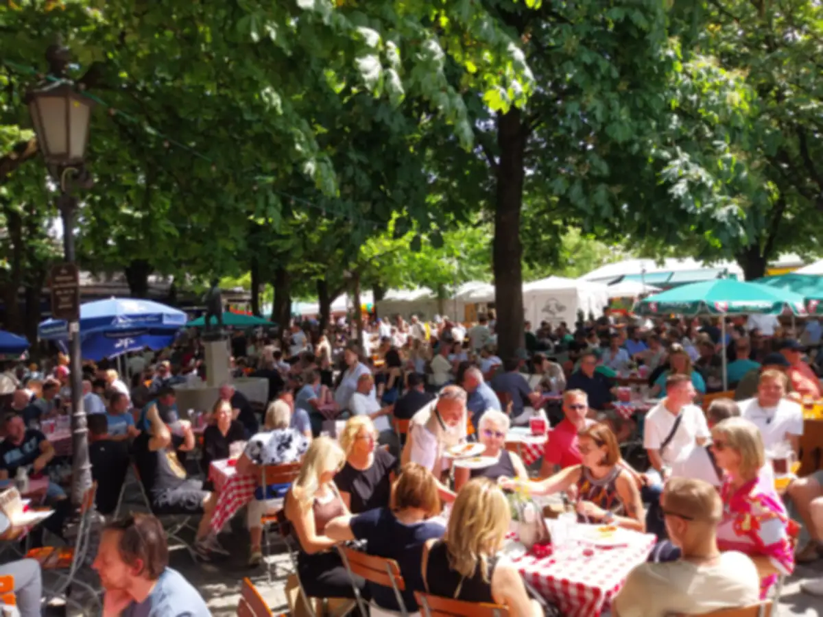Viktualienmarkt beer garden in Munich with tables under trees and rotating Munich brewery beer