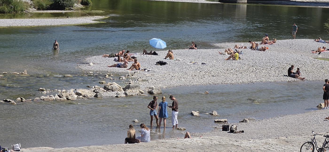 People relaxing and cooling off by the Isar during a hot summer day in Munich