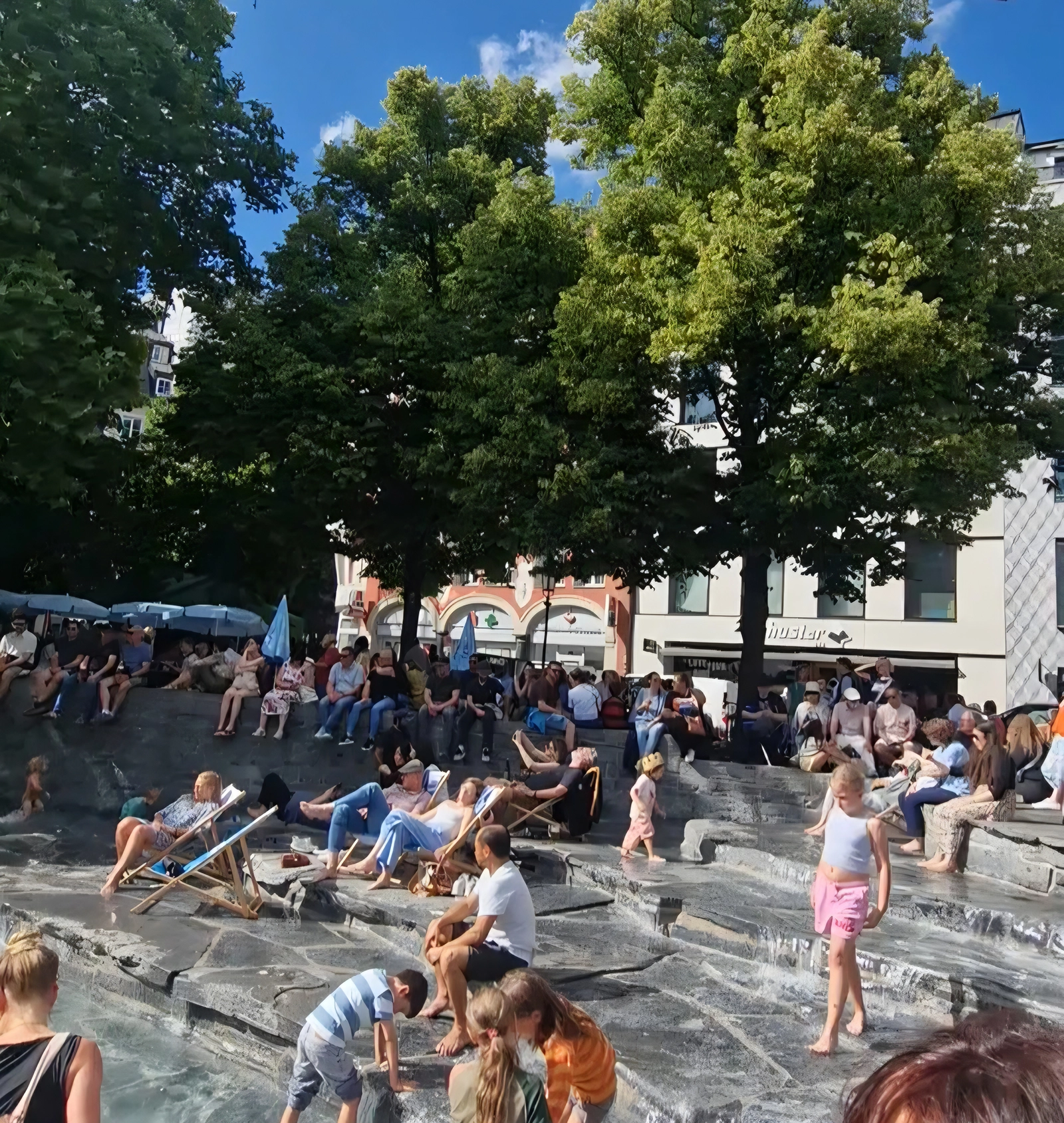 People cooling off at the Rindermarkt fountain during a Munich heatwave